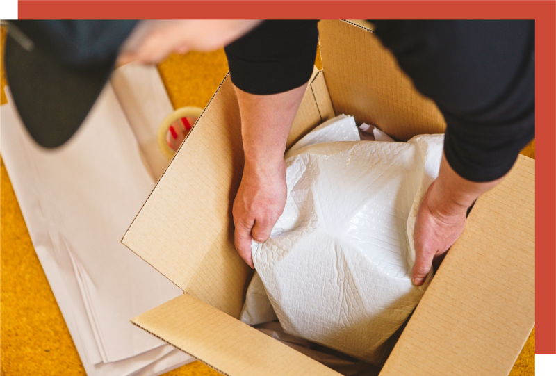 Packing boxes with care, wrapped fragile items being placed in moving boxes